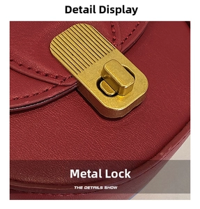 Close-up of golden brushed rotating lock on dark red textured leather crossbody bag