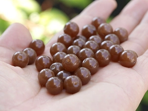 Macro shot of amber-colored translucent beads held in hand for size and texture detail