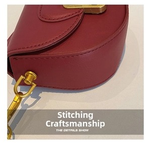 Detailed close-up of stitching on red leather saddle bag with vintage gold buckle