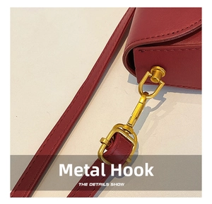 Detailed close-up of a burgundy saddle bag with gold metal swivel hook and leather strap