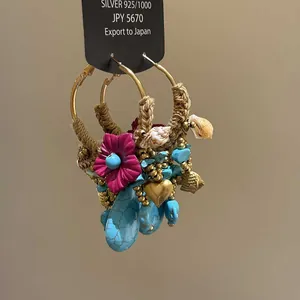 Detail of Bohemian hoop earrings with turquoise, shells, heart charms, and woven rope