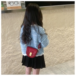 Toddler girl wearing a small red leather saddle bag with a golden turn-lock closure