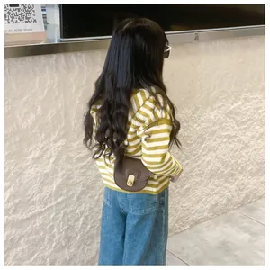 Rear view of a girl in a yellow striped sweater and denim pants with a brown saddle bag
