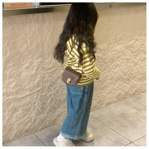 Close-up of a child wearing a brown PU leather saddle bag with golden buckle closure