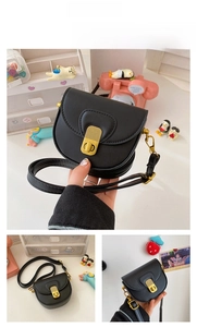 Detail of small black faux leather saddle bag for girls with golden metal twist lock