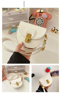 Detail of creamy white crossbody saddle bag for girls with gold hardware and U-shaped stitching