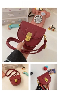 Detail of red PU leather saddle bag with vintage gold buckle and long strap