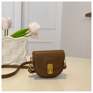 Close-up of brown vintage mini saddle bag with golden clasp and adjustable strap