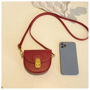 Detail view of mini dark red leather saddle bag with golden metal buckle for kids
