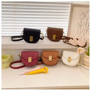 Flat lay of mini saddle crossbody bags in five colors with gold metallic buckles