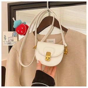 Close-up of a cream mini saddle bag featuring vintage gold hardware and grained leather texture
