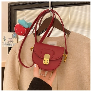 Close-up of a burgundy leather saddle bag for kids with elegant gold metal twist lock buckle