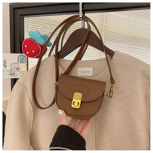 Detail of a mini brown leather saddle bag for girls with a vintage gold snap closure