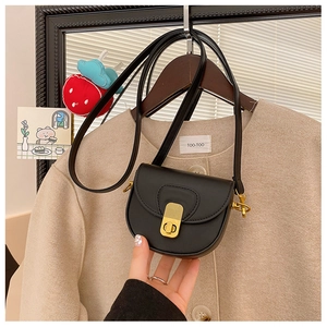 Detail of a black leather mini saddle bag with vintage gold buckle on a stylish coat