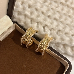 Irregular gold C-shape hoop earrings with textured finish and pave zircon border