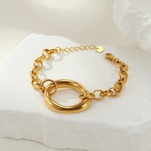 Minimalist gold chunky chain bracelet with oval link and polished tag on white stone