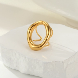 Polished gold organic fluid ring displayed on a natural white textured stone