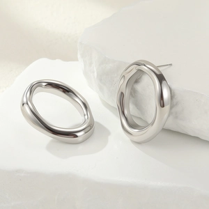 Macro detail of silver liquid metal style irregular oval earrings on a stone prop