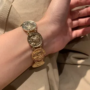 Dettaglio di un bracciale con monete d'oro vintage con rilievo di ritratto e perline