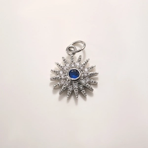 Macro view of sunburst pendant with deep blue center stone and diamond accents