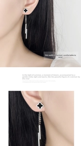 Detail of silver clover earrings with black onyx pendants and long elegant tassels