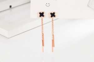 Detailed macro view of black clover earrings with long tassels in a rose gold finish