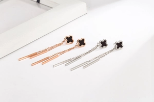 Detailed macro view of four-leaf clover drop earrings with tassels in rose gold and silver