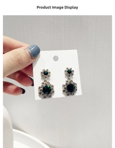 Détail de boucles d'oreilles vintage avec pierres vert foncé et accents argentés