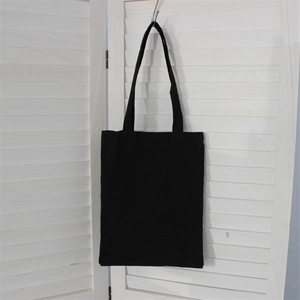 Detail view of a thick black canvas tote bag hanging against white shutters