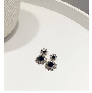 Détails de boucles d'oreilles vintage avec pierres vert émeraude et auréole de cristaux