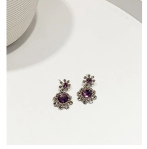 Gros plan de boucles d'oreilles flocon en argent avec cristal violet et halo de zircons