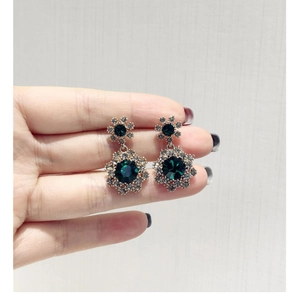 Détail de boucles d'oreilles fleur en cristal vert foncé avec base dorée à la main