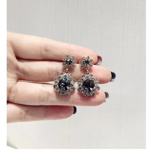 Détail de boucles d'oreilles vintage avec cristaux gris foncé et pavé de diamants brillants