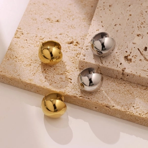 Minimalist hollow ball stud earrings in gold and silver finish on stone display