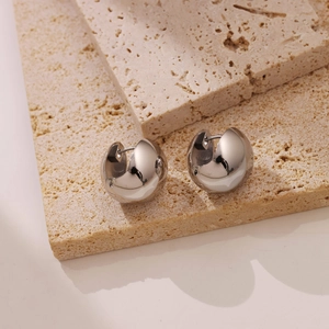 Minimalist silver polished hollow dome stud earrings on a natural stone display pedestal
