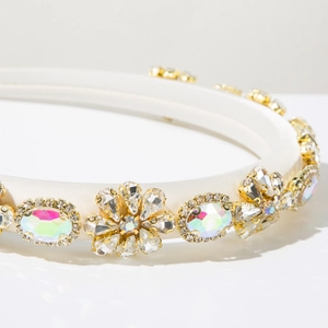 Macro shot of white satin padded headband with colorful crystals and gold metal floral settings
