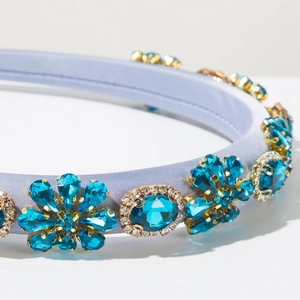 Macro detail of Baroque headband with blue crystals and floral metal claws on satin