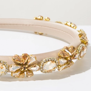 Close-up of champagne satin headband with amber rhinestones and baroque floral details