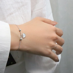 Minimalist silver beaded bracelet featuring a heart shell pendant on a female wrist