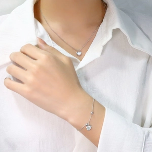 Detailed view of silver heart shell necklace and matching beaded bracelet on model