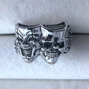 Macro detail of gothic joker ring featuring dual smile and cry mask design in retro silver