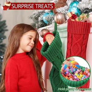 Detail of red and green cable knit Christmas stockings held by a girl near a fireplace