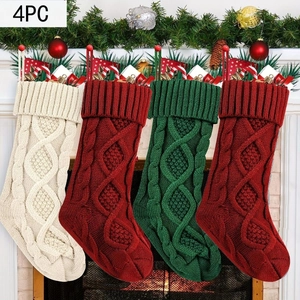 Set of four knitted Christmas stockings in ivory, red and green hanging on a white mantel
