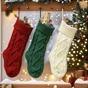 Close-up of three knitted Christmas stockings with cable patterns and festive gift fillers