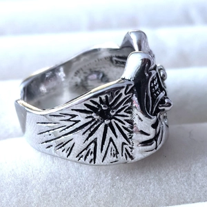 Macro side view of gothic silver ring showing relief mask and sunburst textures