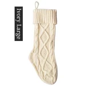Detail of ivory white knitted Christmas stocking showing cable stitch pattern and loop