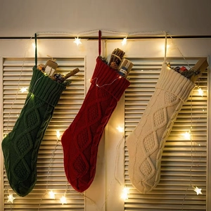 Close-up of three knitted Christmas stockings in green, red, and white with cable patterns