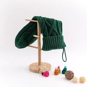 Detail of dark green cable knit Christmas stocking hanging on a light wooden stand