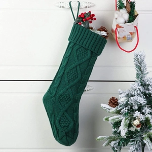 Close-up of dark green cable knit Christmas stocking with hanging loop on white cabinet