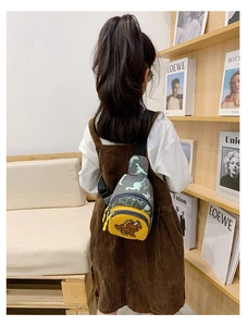 Kid showing the green dinosaur chest bag on back in a warm Nordic home setting